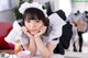 A woman in a maid outfit sitting at a table with a cup of tea.