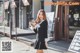 A woman in a black dress is walking down the street.