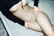 A woman in fishnet stockings is sitting on a couch.