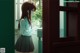 A girl in a school uniform looking out a window.