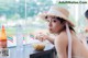 A woman in a straw hat eating noodles at a table.