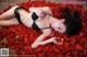 A woman laying on a bed of red rose petals.