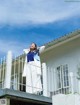 A woman standing on the balcony of a white house.