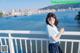 A young woman standing on a railing by the water.