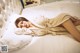 A woman laying on a bed in a beige robe.